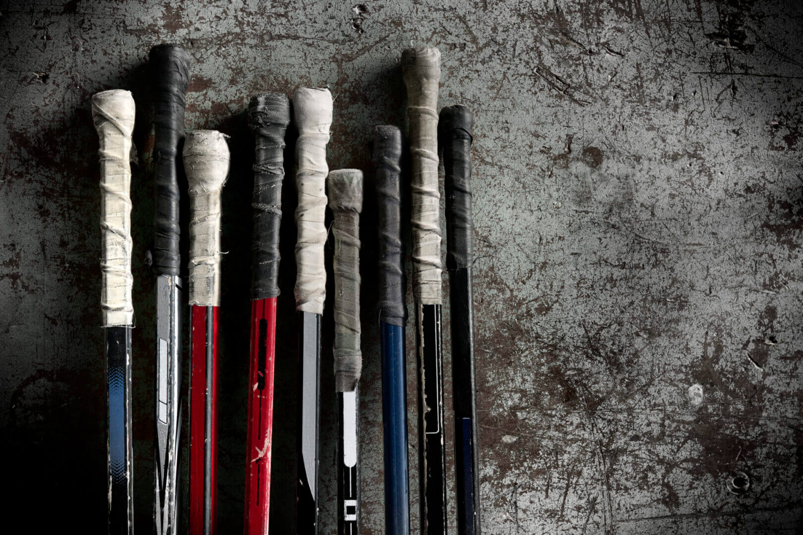 Hockey sticks with taped grips on ground.